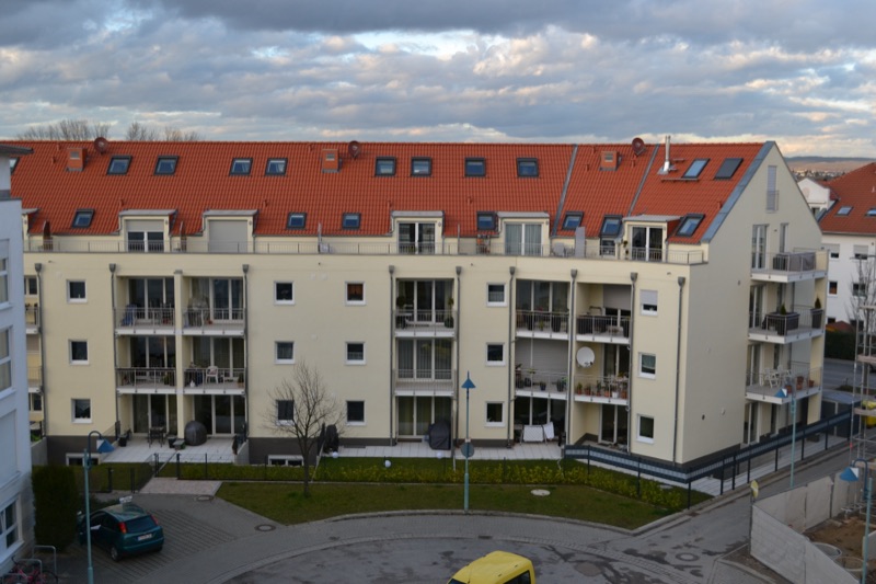 Fertiggestellte Wohnanlage mit heller Putzfassade und rotem Ziegeldach